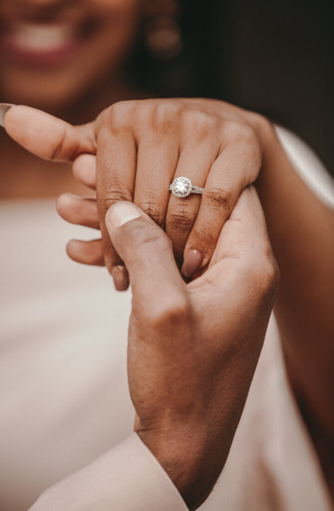 Eine männliche Hand hält eine weibliche Hand, die einen Diamant-Ring trägt