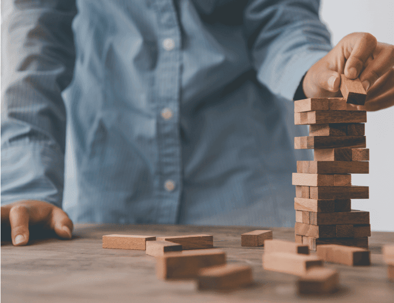 Ein Mann stapelt Holzklötze aufeinander zu einem Turm.