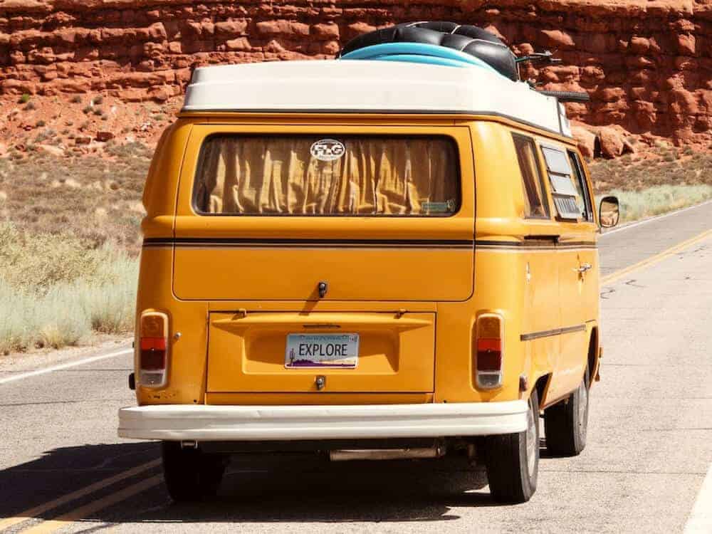 Ein oranger VW-Bus auf der Straße in den Bergen von Amerika.